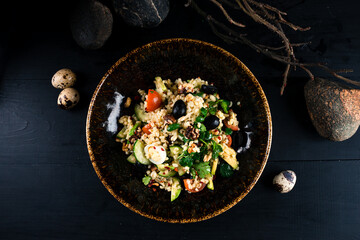 Salad with rice, olives, cucumbers, avocado, eggs, cherry tomatoes, walnuts, spices and greens.