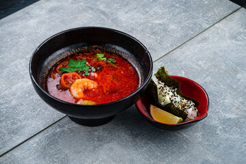 Asian red spicy soup with shrimp, tomatoes, lime and herbs.