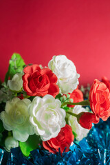 Bouquet of artificial flowers on a red background with copy space. Selective focus