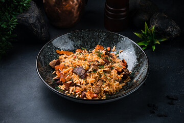 Pilaf with with lamb, raisins, almonds, carrots, tomatoes, onions and herbs in a plate.