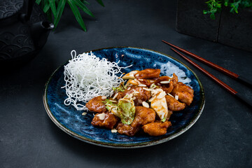 Asian food chicken fillet with apples, almonds, herbs and sauce with chopsticks.