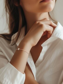 Close-up of a delicate bracelet on a woman's wrist with a white shirt