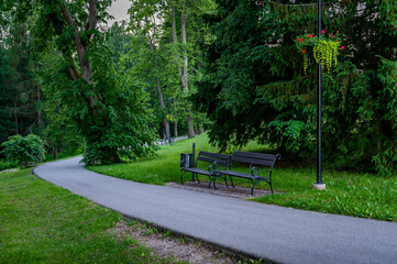 A pedestrian path leads through the park with benches. Smiltene Old Park, Latvia.