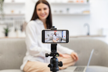 Demanding tutor using modern smartphone with tripod for online training. Caucasian woman with...