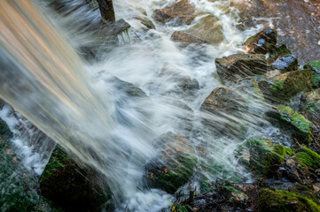 Water splashing from impact onto rocks. Stream of clean falling water. Close-up.