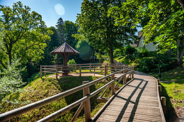 Wooden boardwalk leading through the park with an observation deck and a mushroom-shaped pavilion. Smiltene Old Park, Latvia.