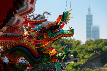 Fototapeta premium Close up view of a Taiwanese temple decorated with colorful sculptures of sacred & auspicious animals ( dragons ) in traditional mosaic art & landmark 101 Tower in background in Taipei, Taiwan, Asia