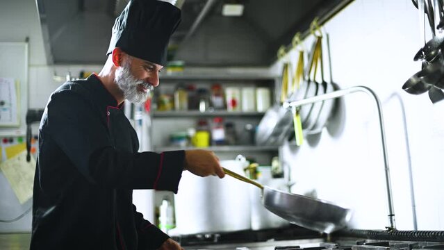 Mature chef jumping verdures in a pan