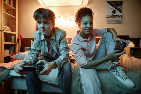 Portrait of two teenagers playing videogames together at night and having fun