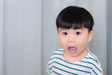 Portrait of funny chubby baby toddler with surprised expression, asian baby making funny face isolated on gray background