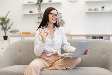 Confident brunette woman in talking on webcam and gesturing with hands. Charming female freelancer...