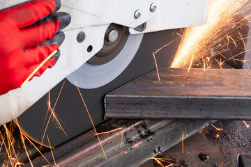 Metal worker cutting a rectangular steel tube using a circular saw, creating sparks, showcasing the...