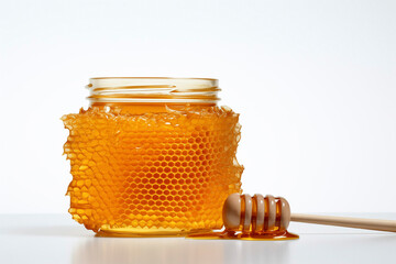 Honey jar in a shape of honeycomb and wooden honey spoon isolated on white background