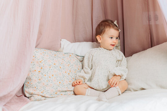 Cute, little baby girl sitting on the pillows