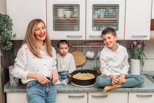 Mom and her children in the kitchen with pasta in the pan for dinner