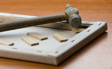Old hammer and disassembled wooden frame on a wooden surface. Repair, restoration or hobby concept