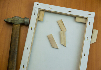 White wooden frame and hammer on a wooden background. Creativity, decor or gift concept