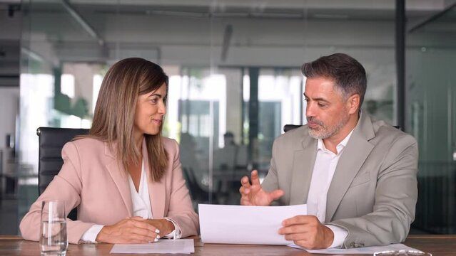 Business woman lawyer attorney showing document to man client providing advisory services, professionals discussing tax papers working in office at meeting. Legal consultancy concept.