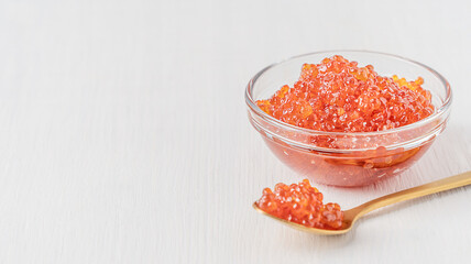 Salty natural salmon red caviar or organic fish roe served in transparent glass bowl on white...