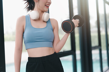 Fototapeta na wymiar sport, fitness, woman, fit, earphones, dumbbell, exercise, healthy, lifestyle, sportswear. dumbbell with a woman in the gym, streaming audio through headphone while training. workout in gym.