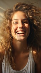 Naklejka premium A woman with curly hair is smiling with her eyes closed. The sunlight is shining on her face.