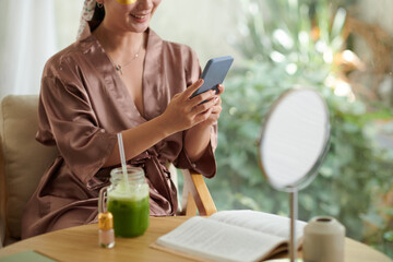 Smiling young woman reading news on social media when getting ready in the morning