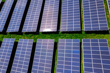 Flying over a solar farm with photovoltaic panels converting solar power to electricity for green energy on agricultural land