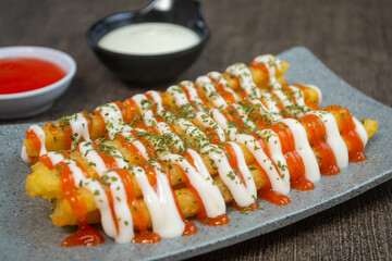 stik kentang keju or fried cheese potato sticks served with chili sauce, mayonnaise and a sprinkle of dried parsley