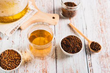 A glass of healthy buckwheat tea and granules for brewing in a bowl on the table