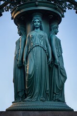 Technical monument in Prague. A cast-iron column with lamps, four women in ancient robes stand on a granite plinth