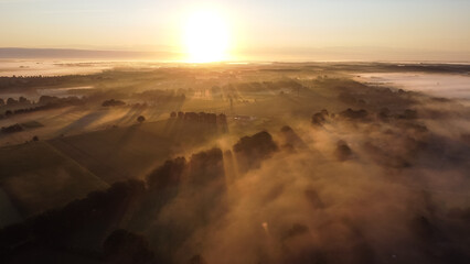 Aerial drone view of meadow landscape in The Netherlands on a sunny, foggy morning. Misty low clouds farmland landscape captured from above.