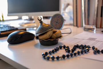 arabic sweets on office desk with quran and rosary