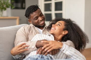 Loving Millennial Black Spouses Hugging And Cuddling While Relaxing Indoors