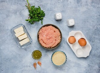 Step-by-step cooking of meatballs stuffed with feta and pesto sauce. Step one, prepared ingredients on a gray concrete background. Step-by-step recipes.