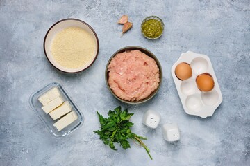 Step-by-step cooking of meatballs stuffed with feta and pesto sauce. Step one, prepared ingredients on a gray concrete background. Step-by-step recipes.