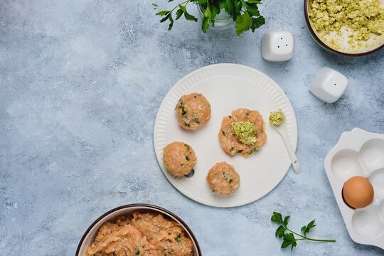 Step-by-step cooking of meatballs stuffed with feta and pesto sauce. Step four, form meatballs stuffed with feta cheese and pesto sauce on a white ceramic board. Step-by-step recipes.