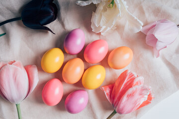 Colorful naturally dyed Easter eggs and beautiful fresh spring flowers in full bloom on table, top view, flat lay style.