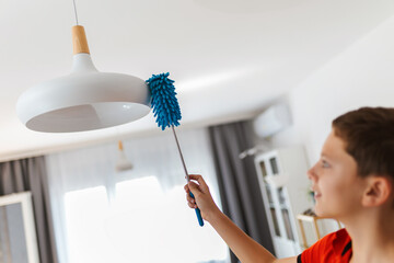 Male child cleaning the chandelier. Doing his chores.