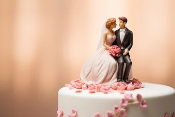 Fotobehang Figurines of the bride and groom on a wedding cake. Close-up of wedding cake topper. Traditional wedding sweets and decorations. © Magryt
