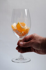 a man's hand hold a glass with mandarin slices