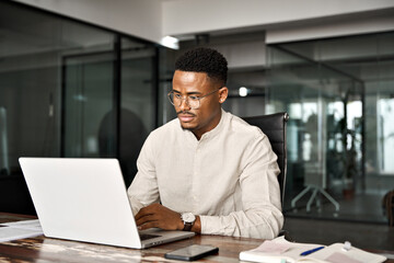 Busy professional male African company employee using laptop working in office. Serious Black...