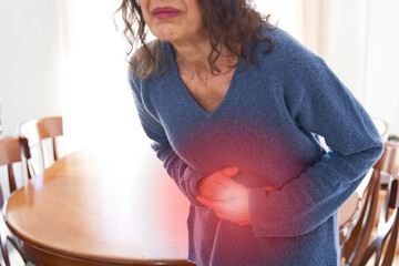 Stomachache and digestive problems. Senior female pressing hands on stomach with painful cramps