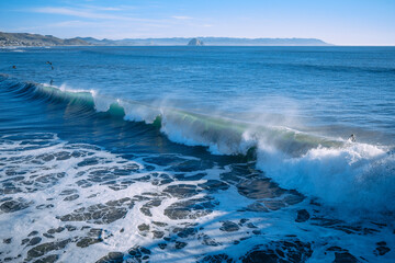 Large waves break off the Pacific shore of California during a great time for surfers surfing....