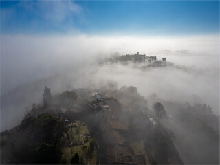 Italy, January 28, 2024: aerial view of the medieval village of Fiorenzuola di Focara immersed in fog. We are in the San Bartolo park near Pesaro in the Marche region