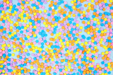 Colorful candy sprinkles background. Above view on a blue background. Pastel Easter color theme.