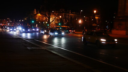 Fototapeta na wymiar Circulation dans une grande avenue parisienne, la nuit tombée, éclairé par des lampadaires et des phares, fluide, promenade nocturne, sortie entre amis, quelques cyclistes, beauté urbaine, effet photo