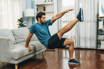 Athletic body and active sporty man using furniture for effective targeting muscle gain exercise at gaiety home exercise as concept of healthy fit body home workout lifestyle. - obrazy, fototapety, plakaty