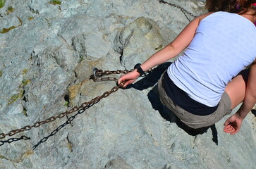 a woman climbs the mountains, hold on to the chain