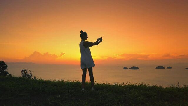 Girl enjoy bright orange sunset sky over seascape. Woman silhouette make photo panorama sea coastline nature landscape. Outdoor lifestyle travel on summer holiday vacation. Impressive colorful scene