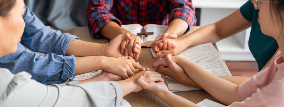 Cropped image of diversity people hand praying together at wooden church on bible book while hold hand together with believe. Concept of hope, religion, faith, god blessing concept. Burgeoning.